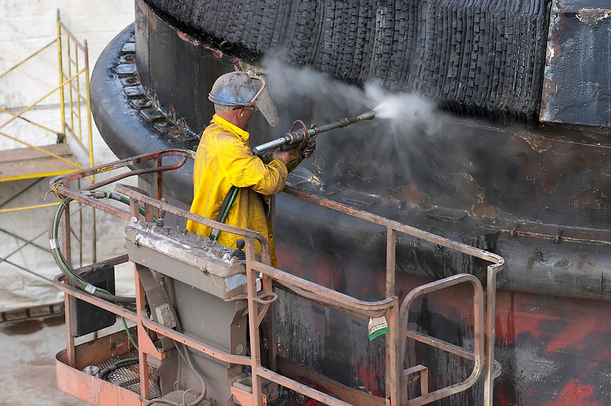 A worker in a yellow raincoat operates a high-pressure hose
