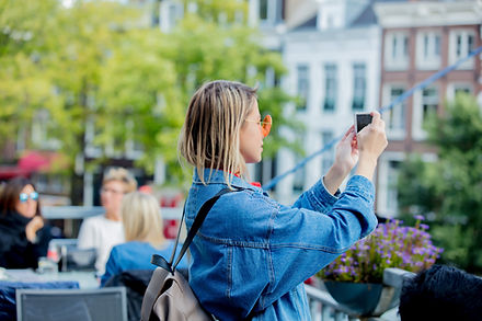 אישה מחזיקה בטלפון נייד ברחוב ומצלמת