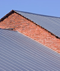 A brick building with overlapping, corrugated metal roofs
