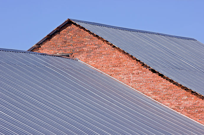 Large scale dark metal profile sheeting installed on a commercial industrial building roof