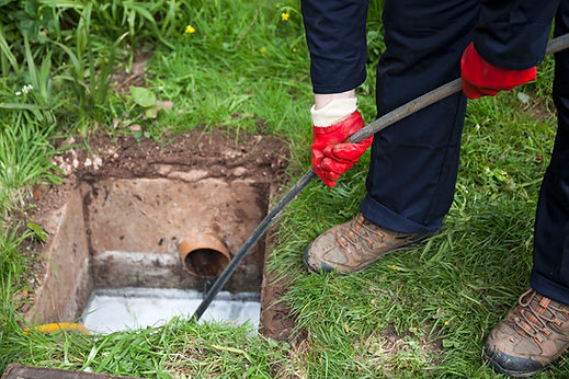 Technician using a drain unblocking rod inside a gully