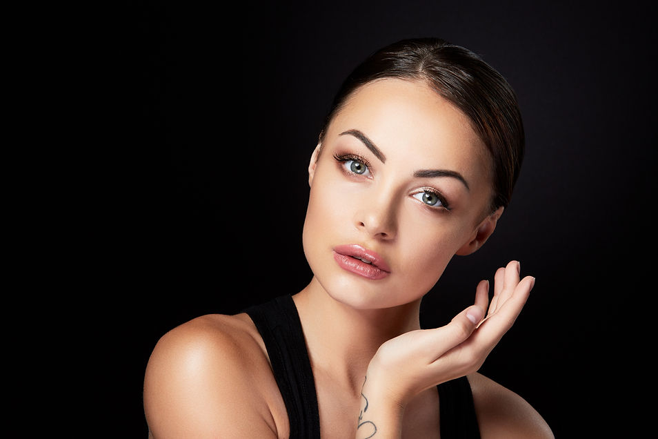 A woman with a neutral expression gently touches her face