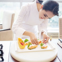 Asiatische Köchin beim Anrichten einer Speise