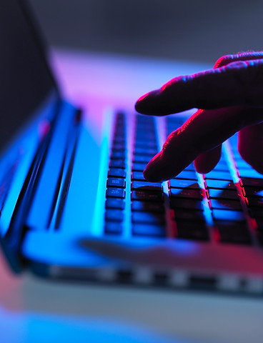 Silhouette of male hand while typing on laptop's keyboard