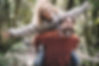Happy Couple smiling and laughing wearing earth tone sweaters woman on the back of her husband playfully enoying a walk in the forest