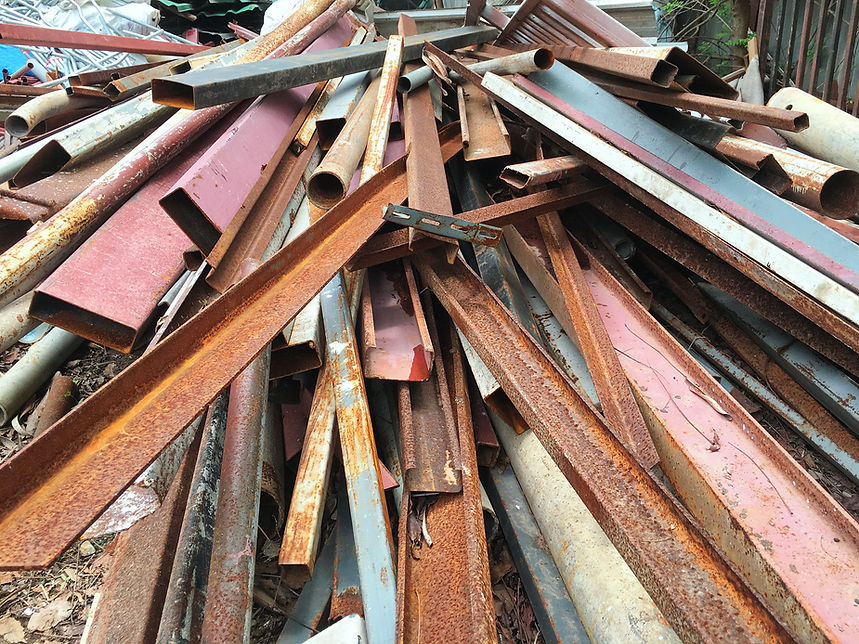 High angle view of a pile of rusty industrial scrap metal pipes and weathered steel beams in a junkyard
