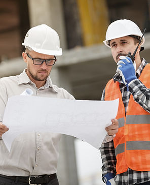 Two construction workers reviewing blueprints at a construction site for project