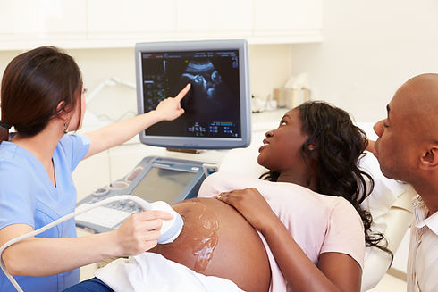 A medical practitioner pointing to an ultrasound monitor screen while showing results to a pregnant couple