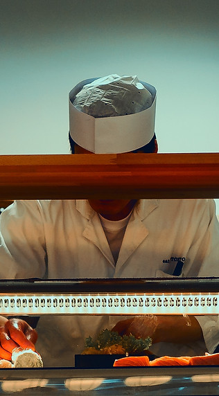 A chef prepares sushi at a sushi bar