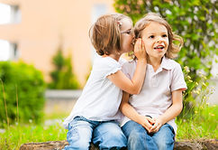 A child whispering a secret in another child's ear