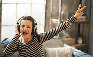 Vista lateral de un cantante interpretando una canción en un micrófono de pie, fondo desenfocado.