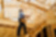 A construction worker stands on a wooden framework, focusing on building a house