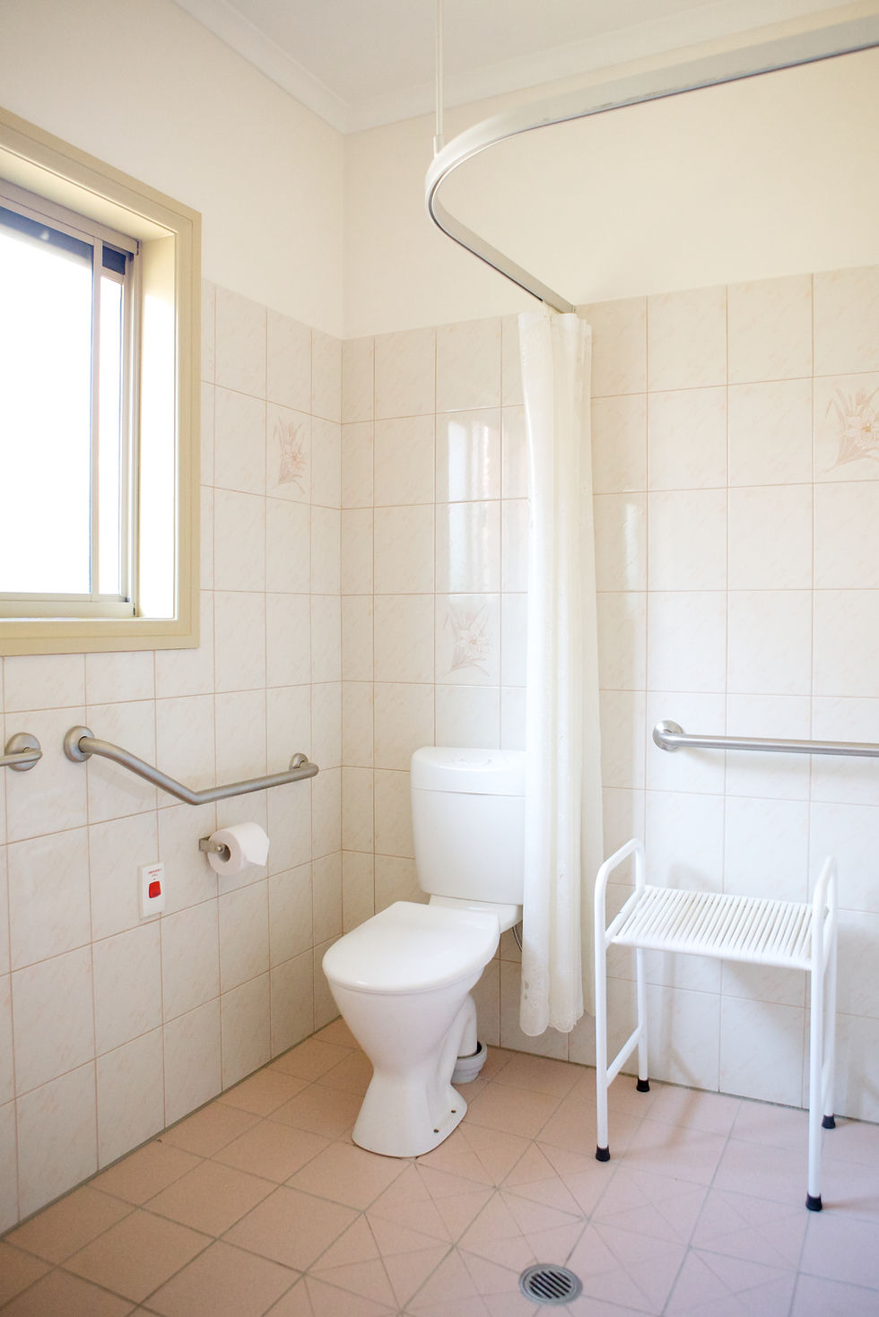 Accessible bathroom with toilet, grab bars, and shower bench