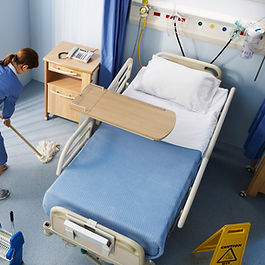 A person in a blue dress mopping a hospital room