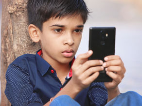 A young boy staring at a smartphone, representing screen addiction in children
