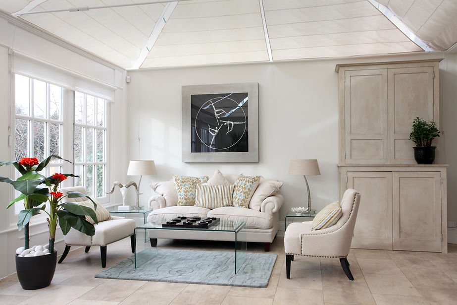 Bright, airy living room with beige sofa, glass table, and abstract wall art