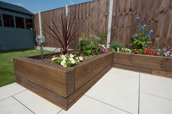 A general view of a back garden patio with white porcelain slabs, tiles, paving and wooden