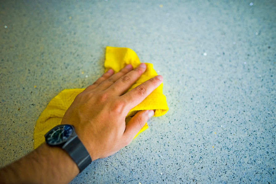 Close-up of a hand cleaning a table with a yellow cloth
