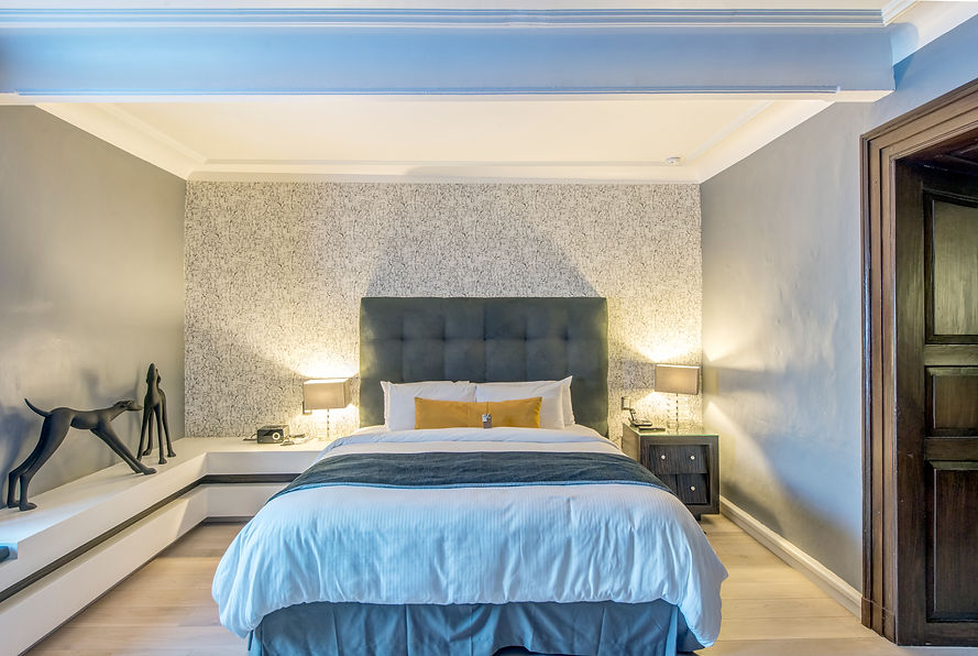 Modern bedroom with grey tufted headboard, blue throw, and mustard accent pillow