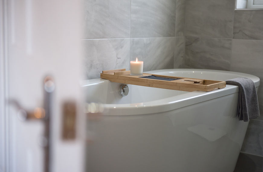 A general interior view of a white free standing roll top bath with floor standing chrome