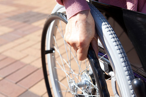A close-up of a hand pushing the wheel of a wheelchair