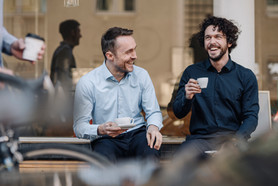 Two men sat laughing drinking coffee