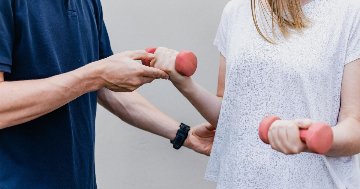 A health professional supporting a person with persistent pain to gradually increase activity and build confidence through positive reinforcement.