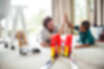 Father and son High Fiving while playing on the living room floor with hot wheels