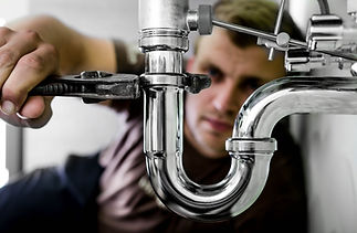 Professional plumber focused on repairing a chrome U-bend pipe assembly