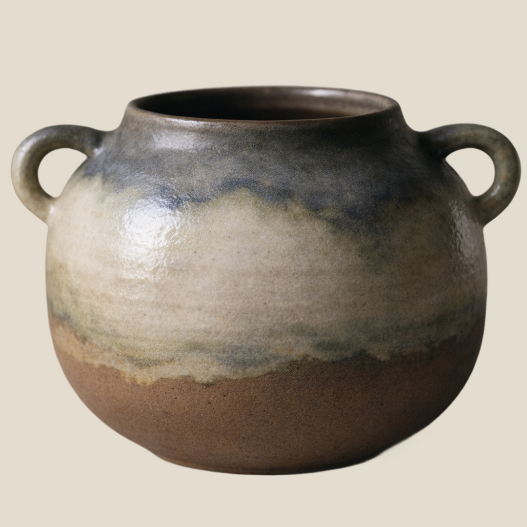 Handcrafted ceramic vase with two handles and a glazed earthy-tone finish on a neutral background.