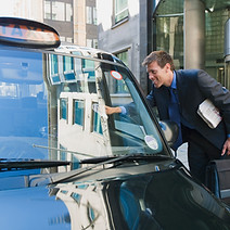 A man in business attire leans into a black cab