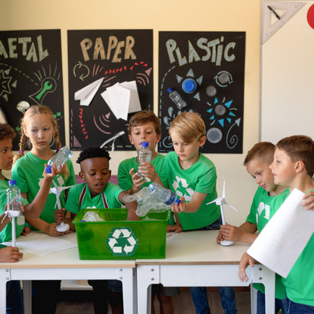 childrens in green t-shirts sorting recycling into bins 