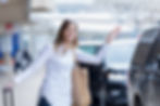 A cheerful woman keeps a hand on her rollerboard handle as she raises her hand to catch th