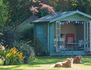 Summer in the garden on a sunny day with the summer house with the doors open and 2 dogs r
