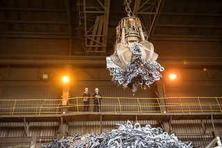 Low angle view of workers watching scrap metal grab in steel foundry
