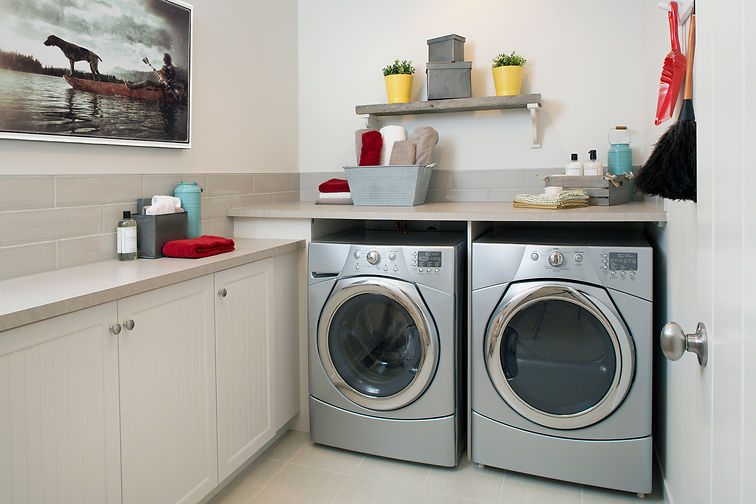 Modern utility room featuring two silver front-loading washing machines under a countertop