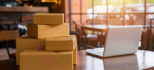 Cardboard boxes stacked near laptop, representing e-commerce logistics SEO blog for ZendEase by Jen Garrucho