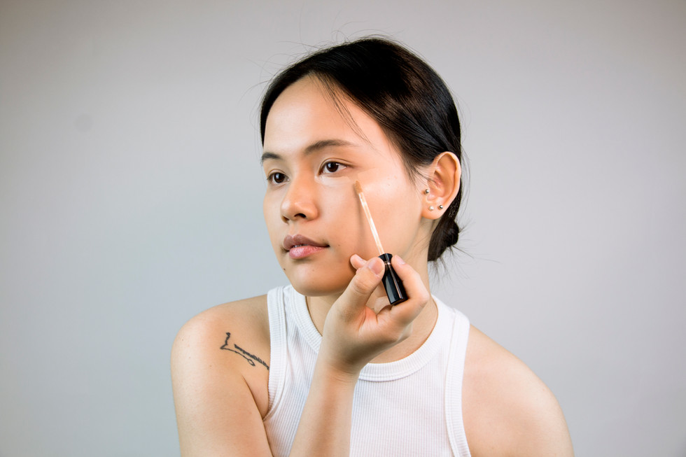 Woman applying concealer under eyes
