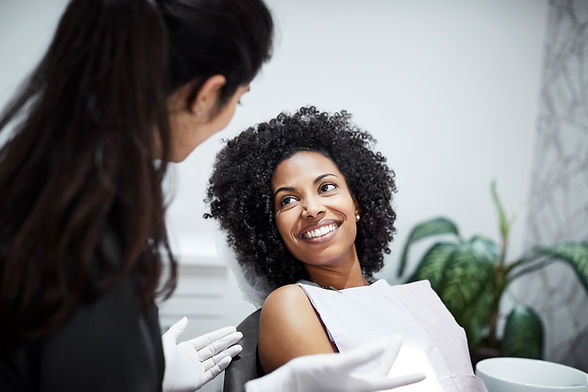 Smiling woman listening to dental doctor. Female dentist is discussing with patient. They