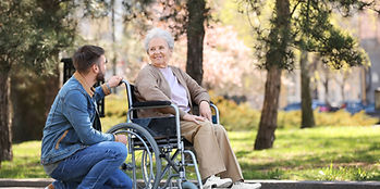 Elderly women in a wheelchair speaking to a male caretaker