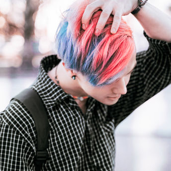 Person with pink and blue hair wearing a checkered shirt