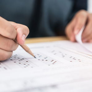 Hand filling out a multiple-choice test with a pencil, focusing on answer sheet bubbles. Soft lighting, close-up.