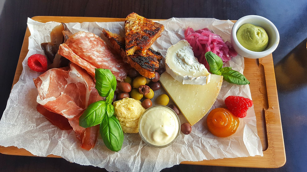 Charcuterie board with cured meats, cheese, olives, dips, and grilled bread on parchment paper