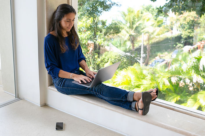 Woman working on a laptop beside tropical plants during a relocation retreat in Costa Rica