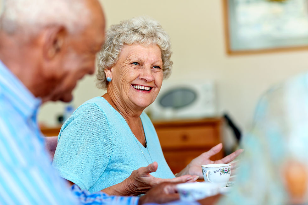 Happy senior woman spending cheerful leisure time with friends in nursing home