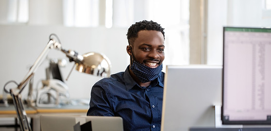 A man with a computer working on a project for client and smiling