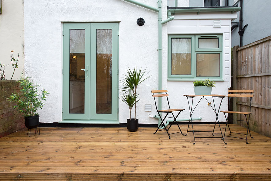 A general exterior view of a back garden patio area with wood decking and potted plants