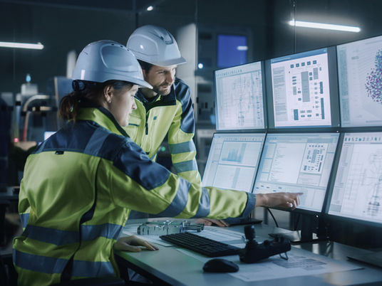 Industriarbetare som håller koll på digital data. Vad händer med deras tillverkning om de får en attack på sina digitala system?