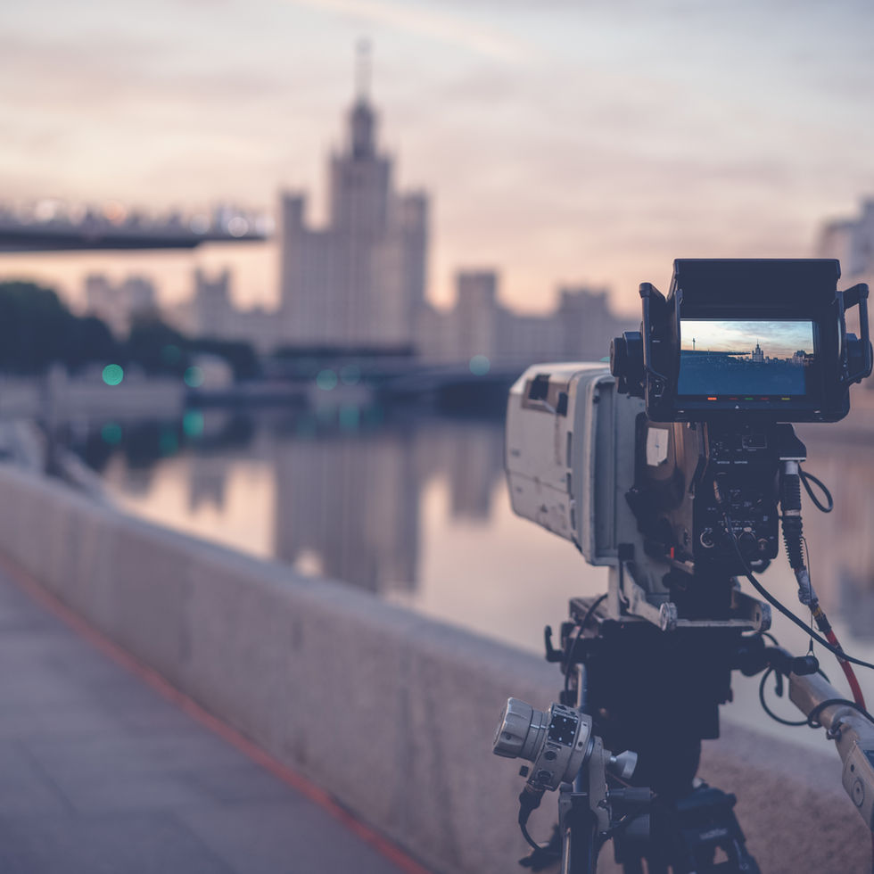 Camera filming a cityscape with water and buildings during the sunset.