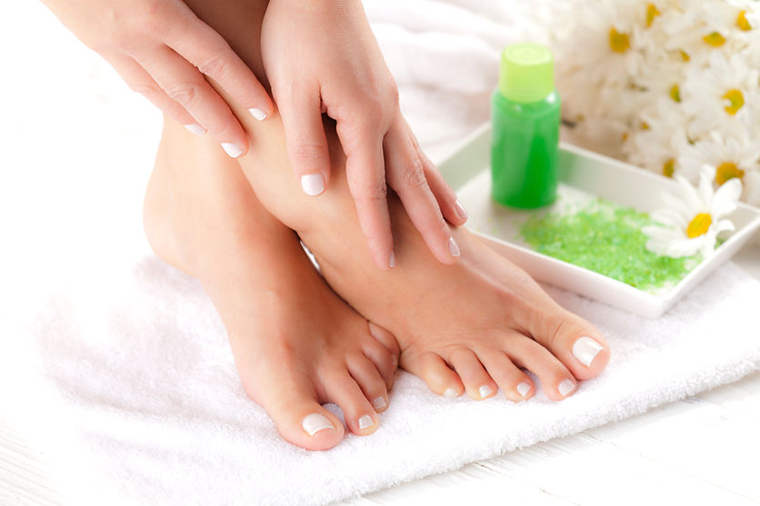 Close-up of a woman's hands massaging her bare foot on a white towel